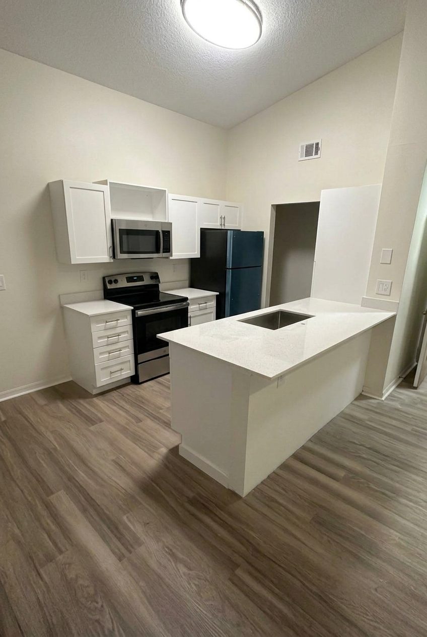 Finished kitchen remodel with white cabinets, quartz island and new flooring