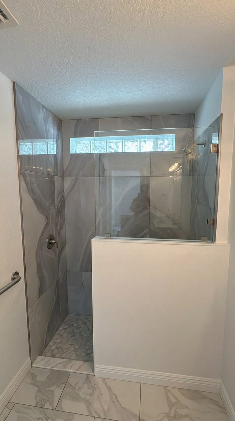 Walk-in shower with large-format marble-look tile being installed