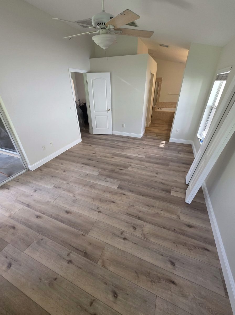 Bedroom with new vinyl plank flooring, white door and fresh baseboards
